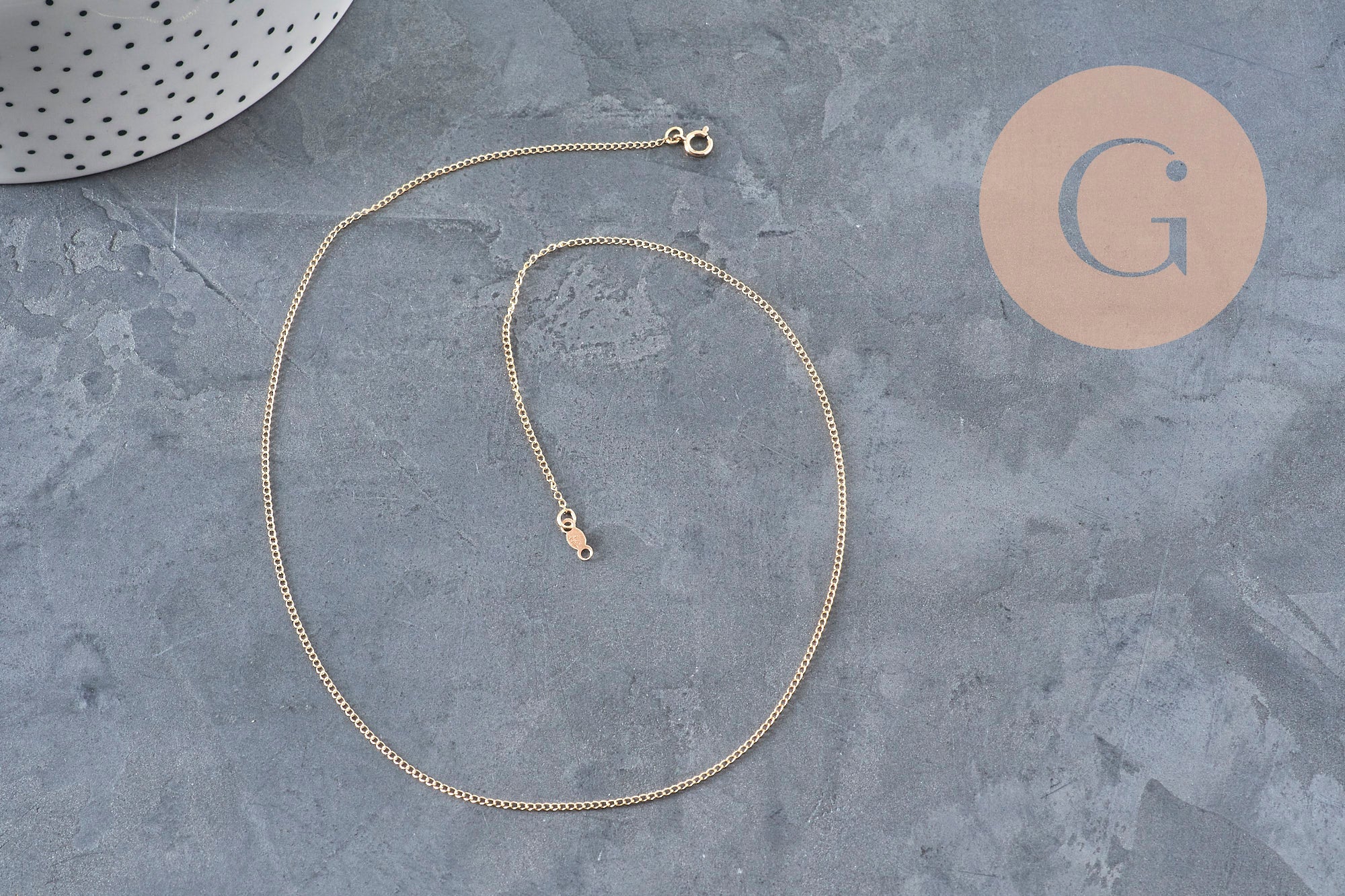 Collier chaîne fine gold-filled 14K de 45.7cm avec fermoir doré sur fond gris.