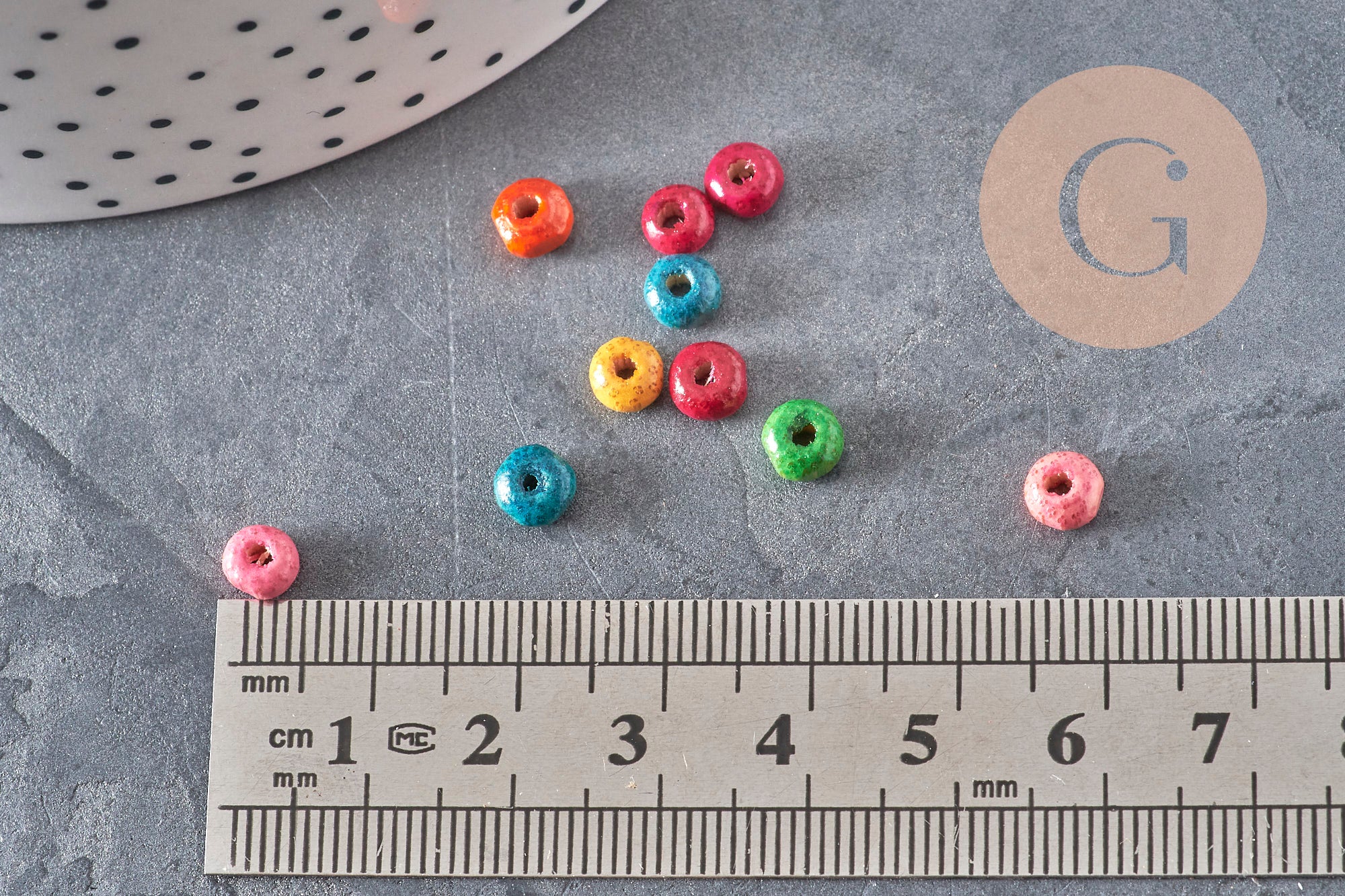 Perles rondelles en bois multicolore 5x3mm pour bijoux DIY, présentées sur une règle pour mesurer leur taille.