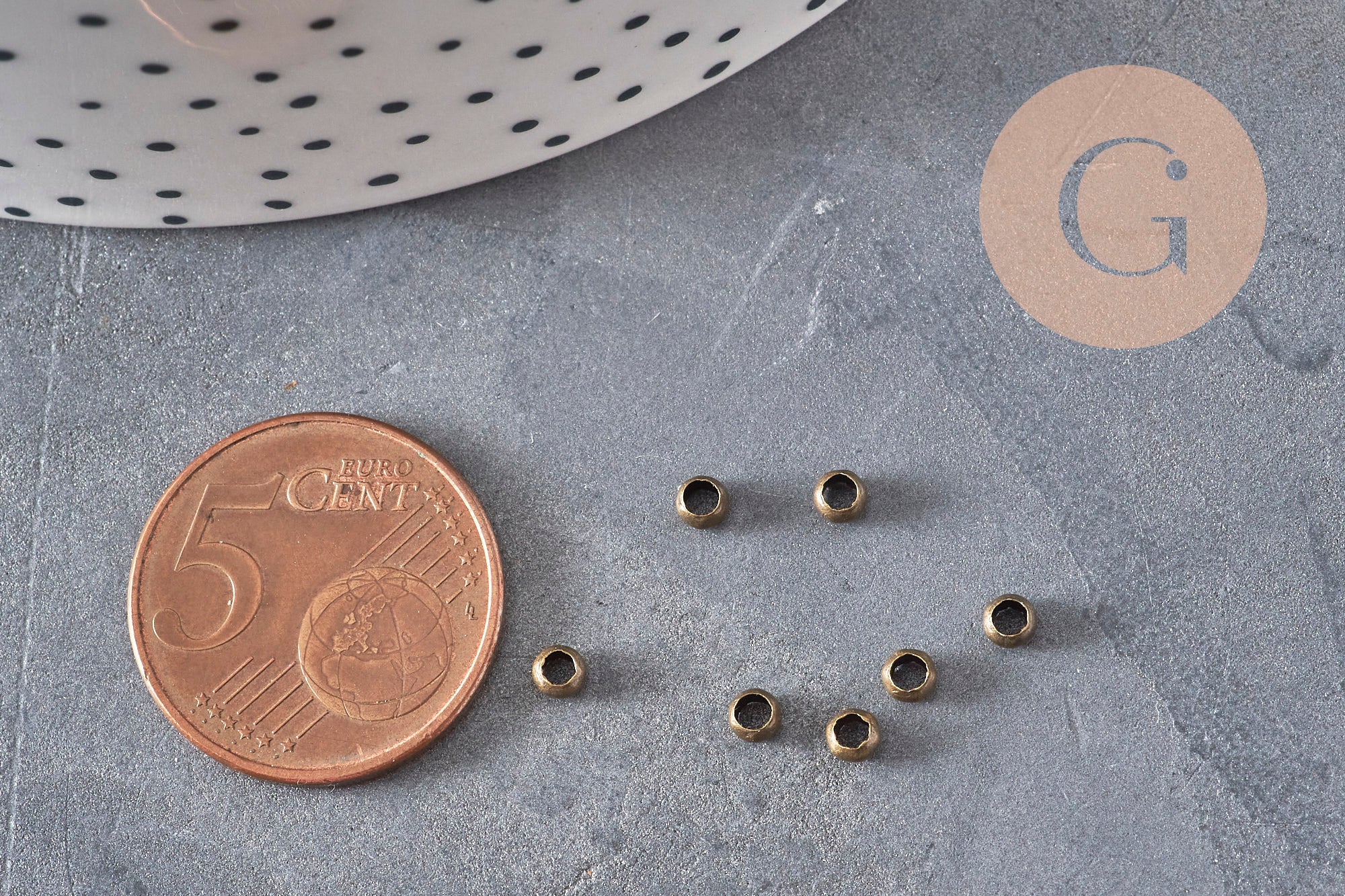 Perles à écraser rondelles en laiton couleur bronze 3x2mm, avec pièce de 5 centimes pour échelle.