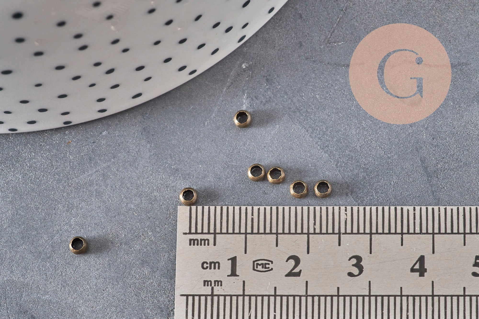 Perles à écraser rondelles en laiton couleur bronze 3x2mm, présentées avec une règle.