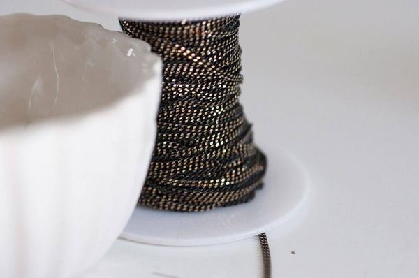 EP-Chaine fine maille plate noire reflets dorés 1.5mm, X 5 mètres G0554