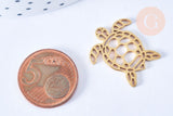 Pendentif tortue acier 201 inoxydable doré 18K 24mm, x1 (G7128) posé à côté d’une pièce de 5 centimes pour comparaison de taille, forme stylisée et finition lisse.