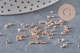 Petites perles à écraser en laiton or rose 2x1.2mm dispersées sur une surface grise.