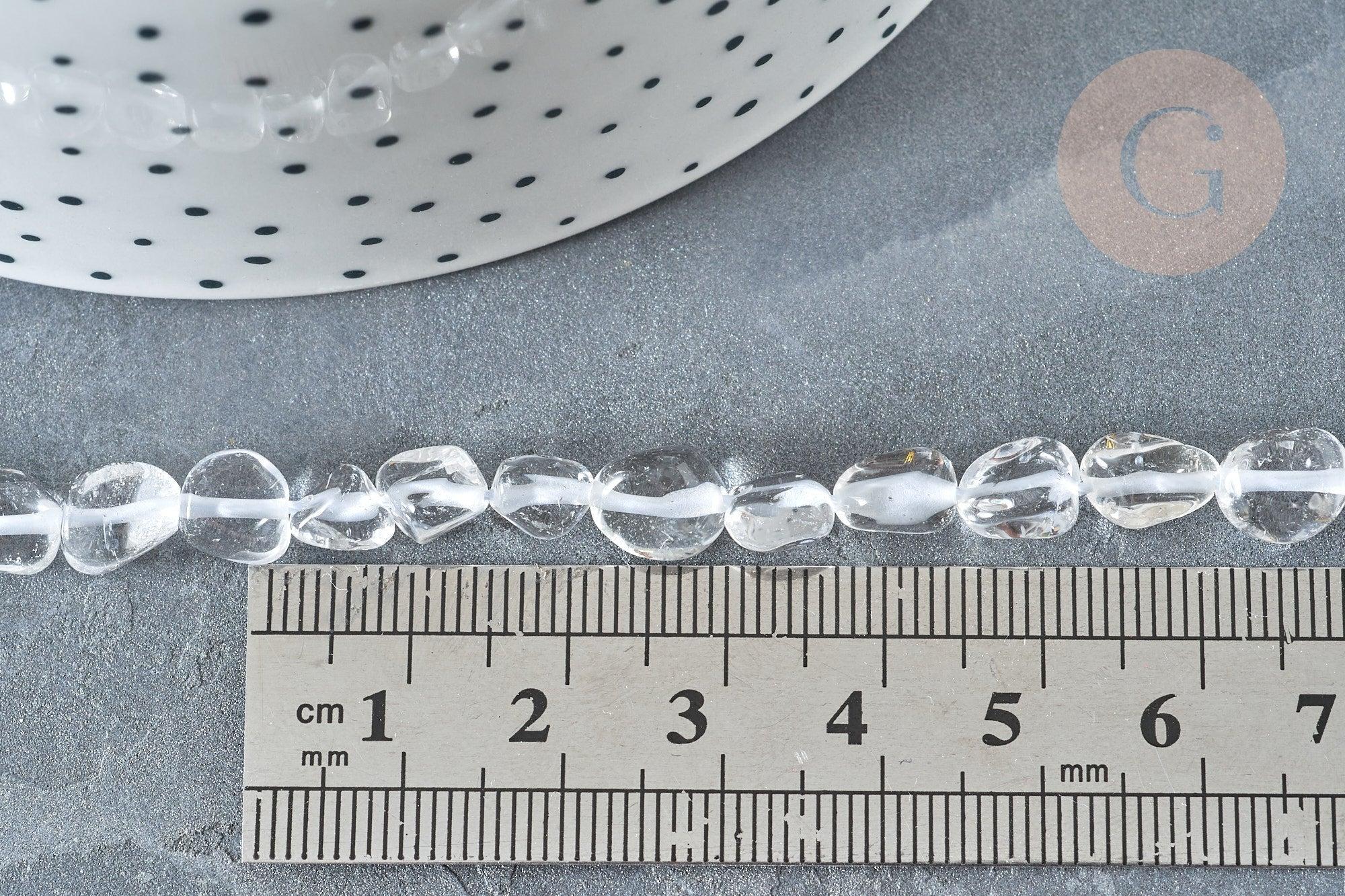 Clear quartz beads, 4–7mm, laid next to a ruler for scale, with a polka-dotted dish edge visible; 40cm strand for jewelry making.